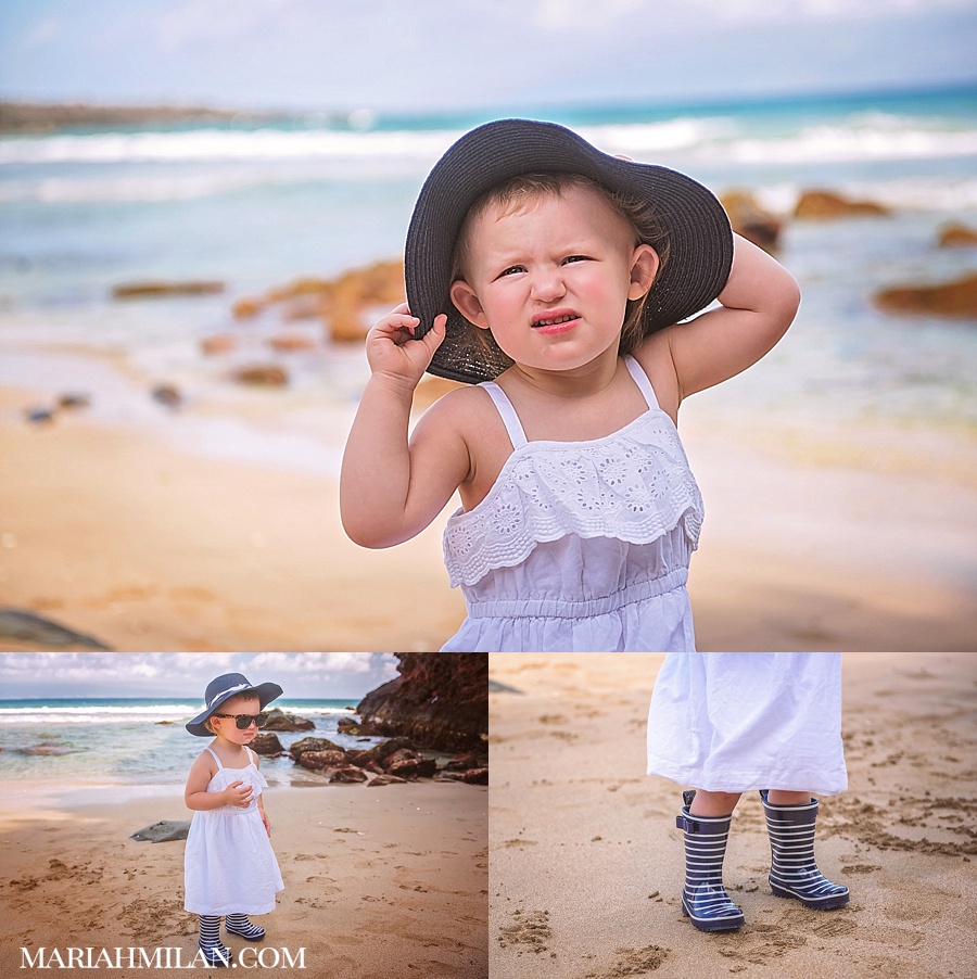 Baby in blue hat and rainboots on the beach