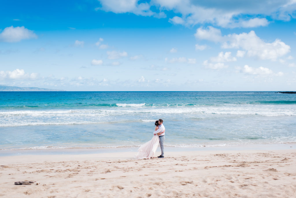 couple standing along the ocean in Kapalua embracing before their maui wedding ceremony