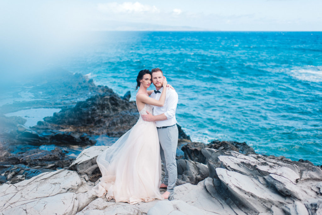 Maui elopement along lava rock cliffs featuring blue water and a gorgeous wedding gown 