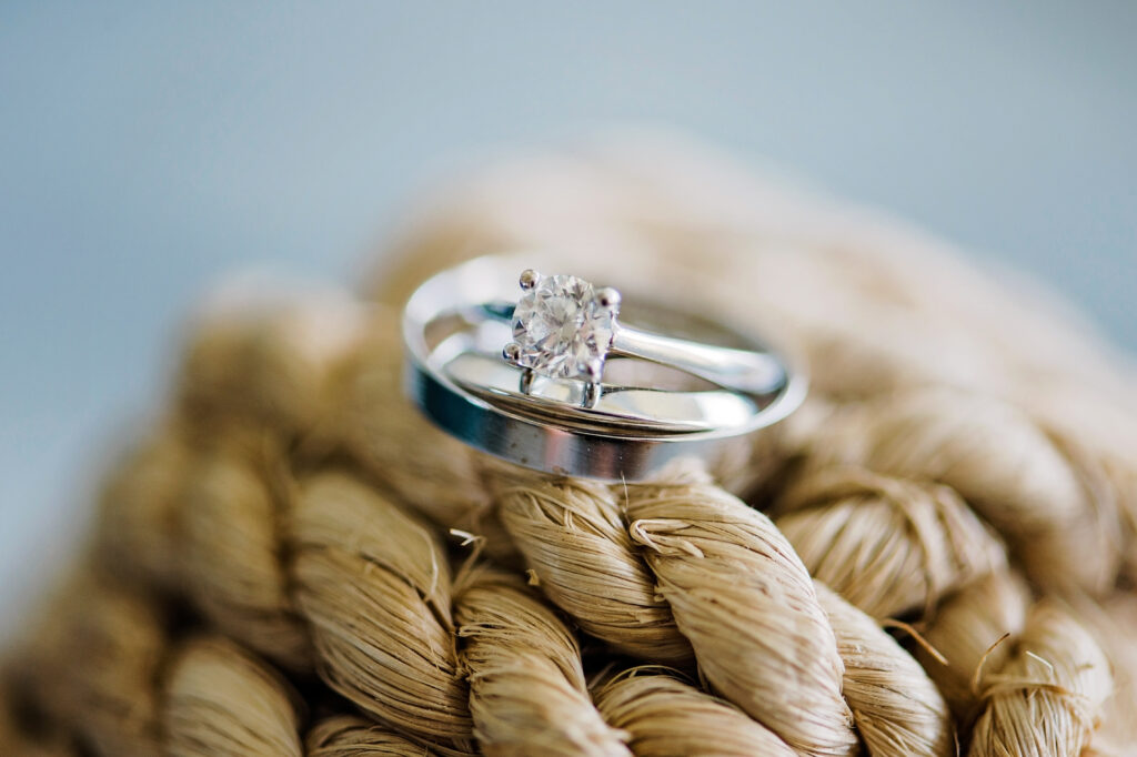 A detailed close-up of the wedding rings placed on textured rope, symbolizing the strength and unity of the couple.