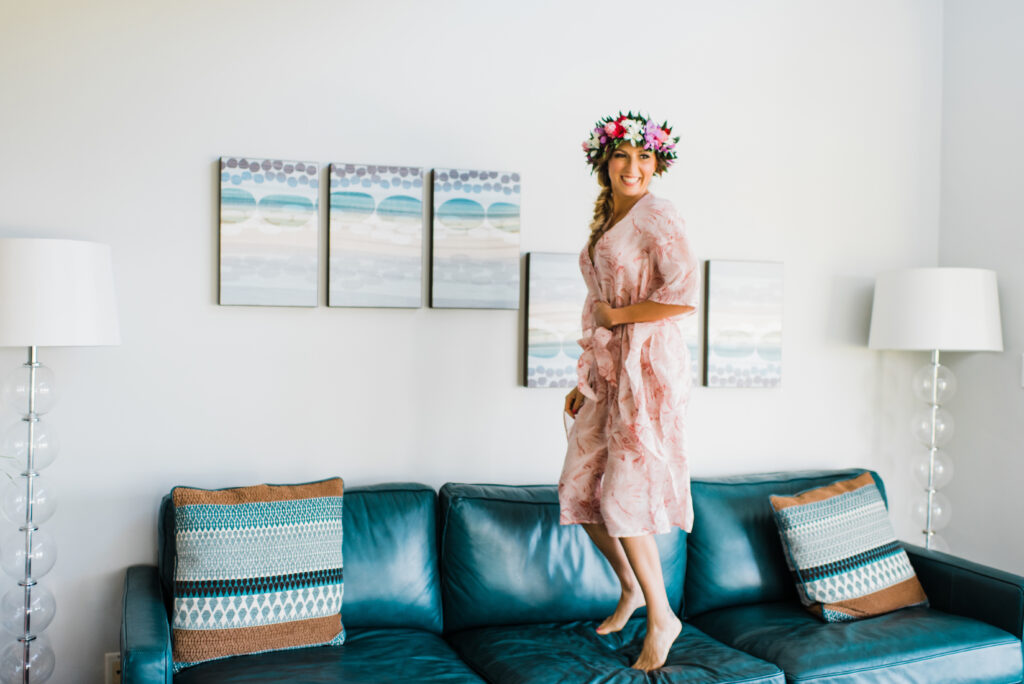 Bride jumping in a cozy room, celebrating the unhurried and personal moments of her Maui elopement.