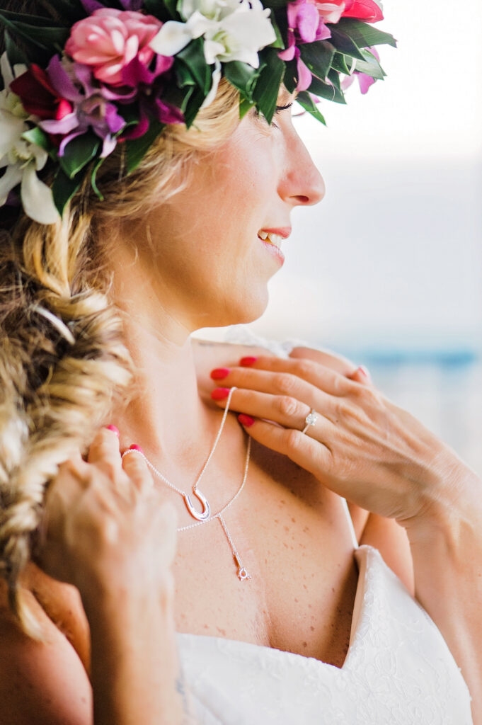 A side profile of the bride adjusting her necklace, her soft floral crown blending beautifully with the golden light.