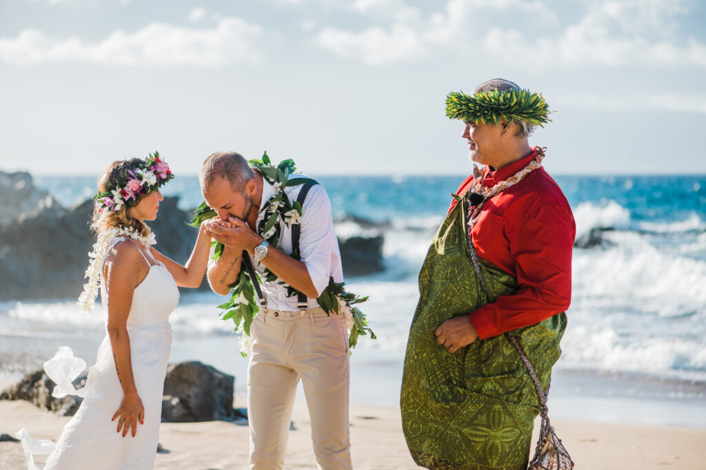 The groom tenderly kisses the bride’s hand, a heartfelt gesture of love and admiration.