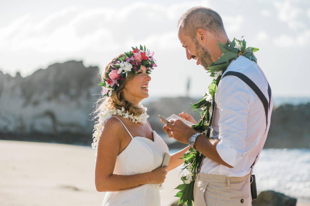 Bride and groom laugh together while reading their heartfelt vows during their elopement.