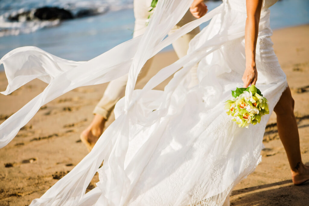A close-up of the bride’s dress flowing in the wind, bouquet in hand—the fabric’s motion echoes the freedom of their day
