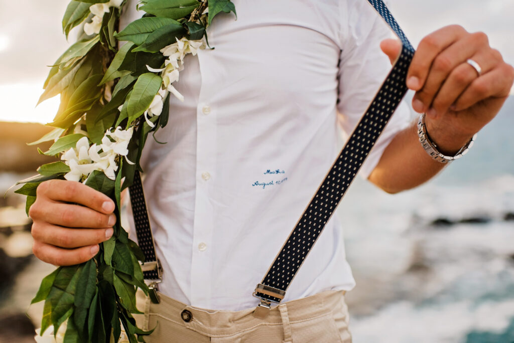 Smiling groom with lei and suspenders.