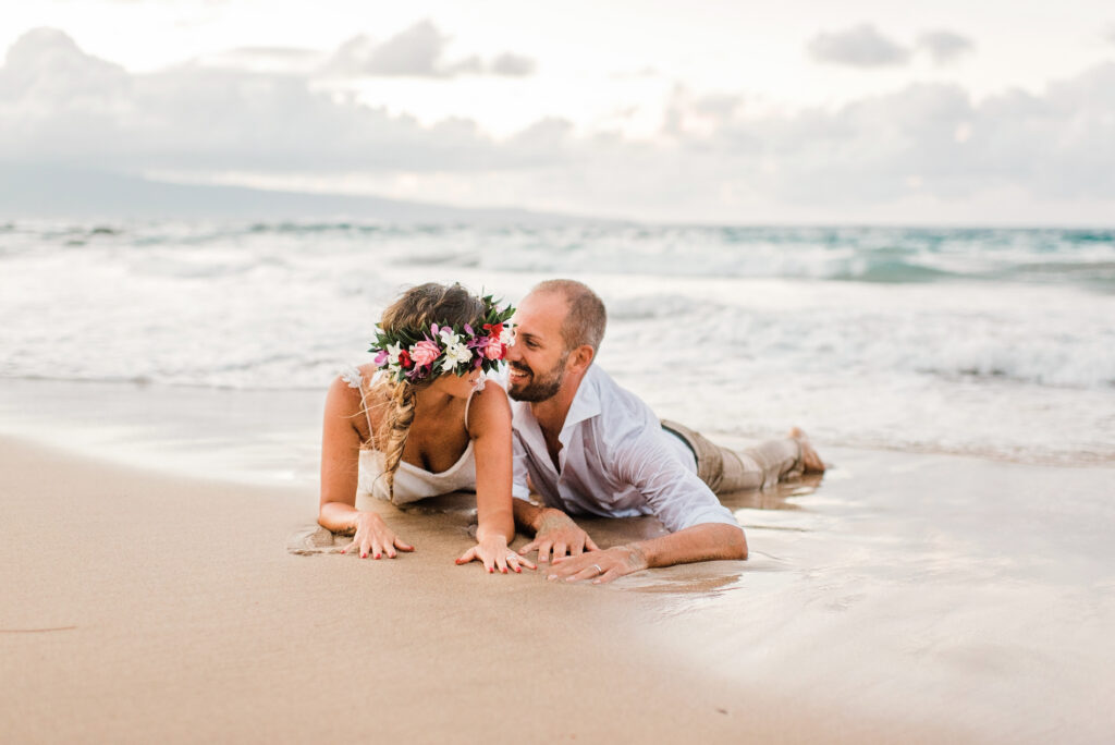 The couple lies on the sandy beach, reflecting on the cherished moments from their longer Maui elopement celebration.