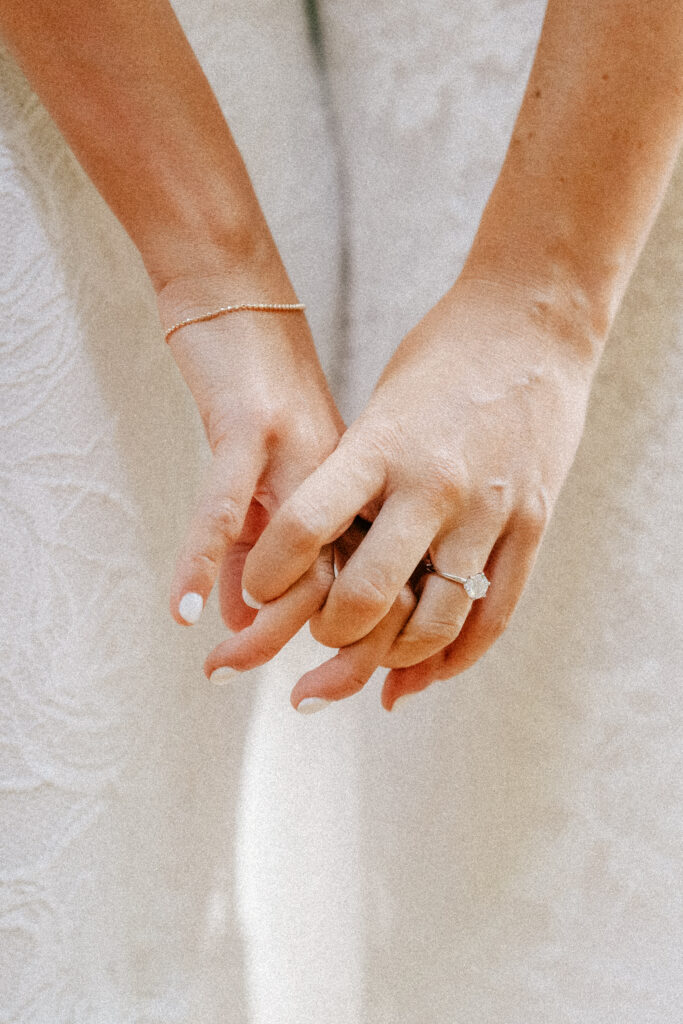 A romantic detail shot of intertwined hands, wedding rings shining in the Maui sunlight.