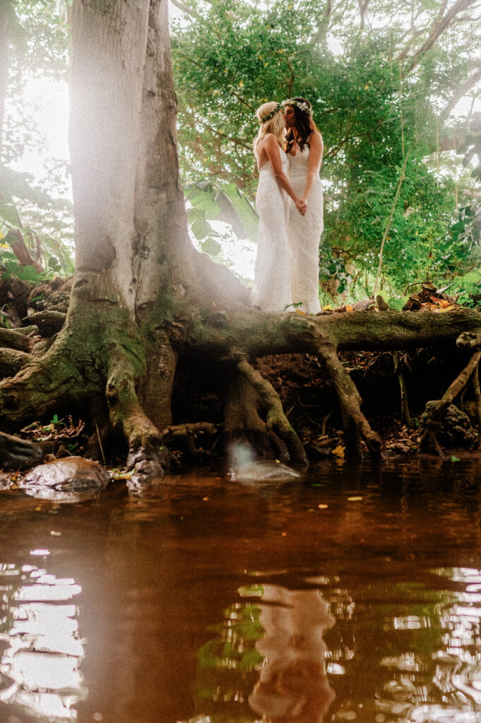 A whimsical portrait of the brides near tree roots, embracing the beauty of Maui’s landscapes.