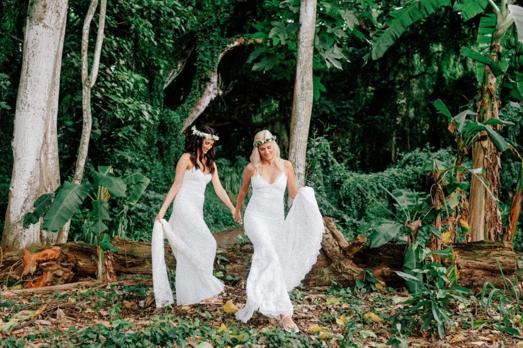 Dori & Natalie twirl joyfully in their wedding dresses beneath Maui’s lush jungle canopy.