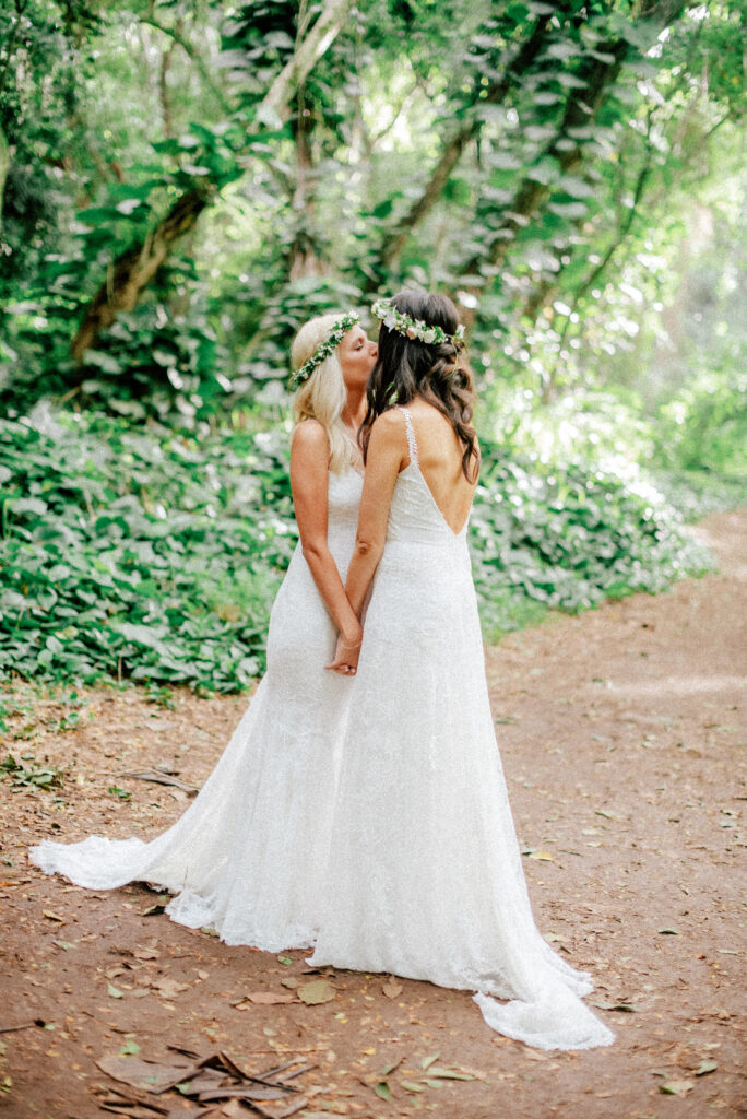 The brides shares a kiss on a forest path, embracing their Maui elopement journey.