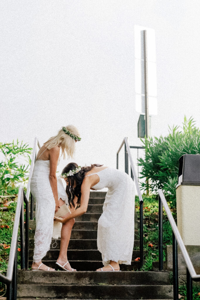 A quiet, emotional moment as one bride helps the other adjust her dress before the ceremony.
