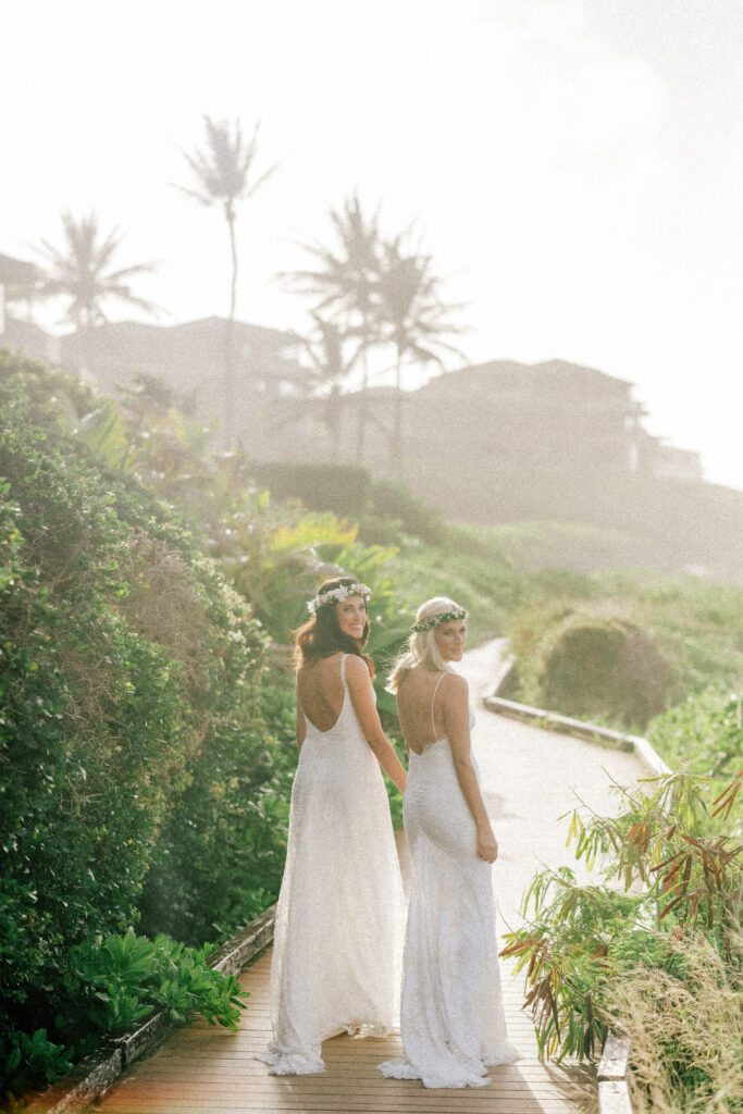 The brides take in the beauty of their surroundings as they stroll toward the beach.