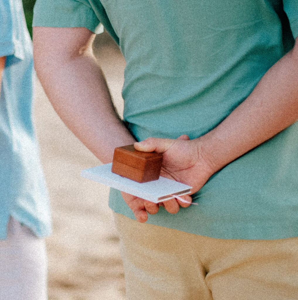 A ring bearer holds the wedding rings in his hands, waiting for the perfect moment.