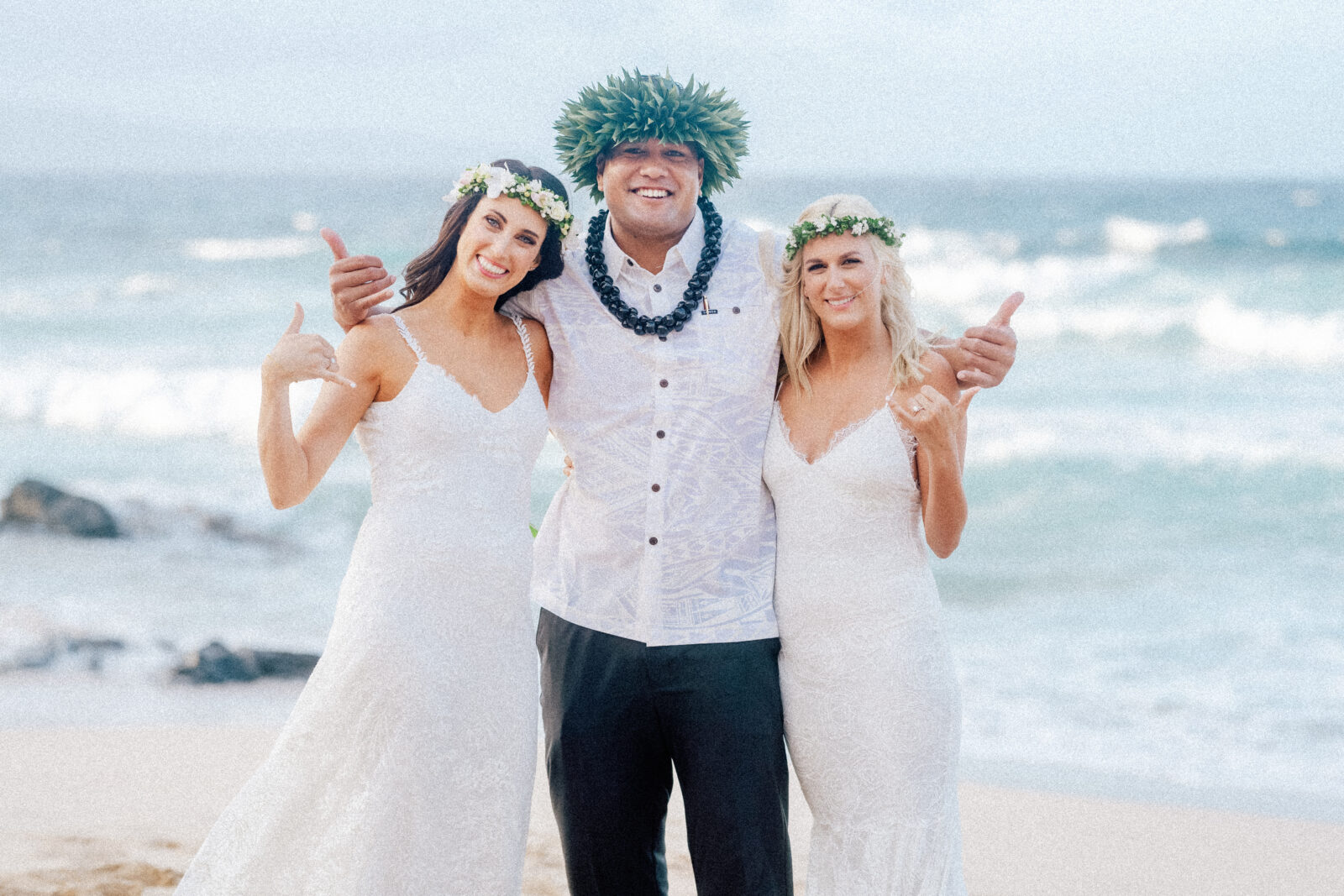 Just married! The brides celebrate their Maui elopement with their officiant on the beach.