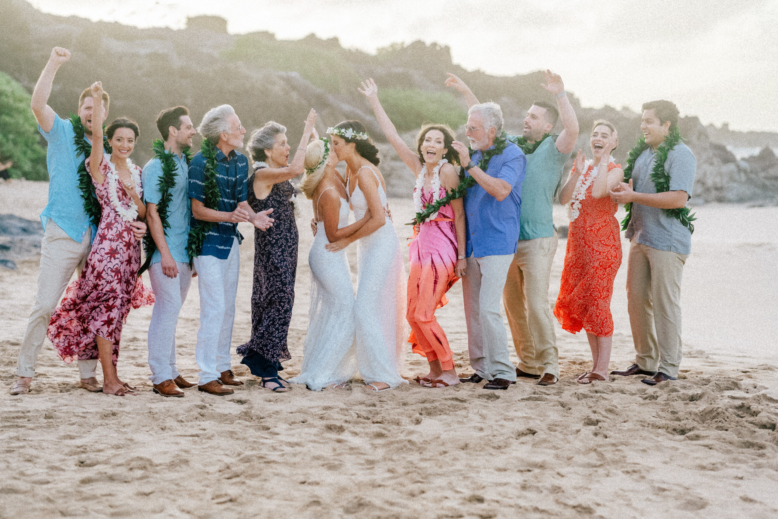 A joyful group portrait of the couple with family and friends on Ironwood Beach, Maui.