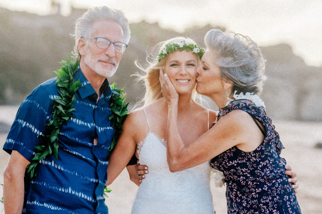 The bride is embraced by her parents, celebrating love and family on this special day.