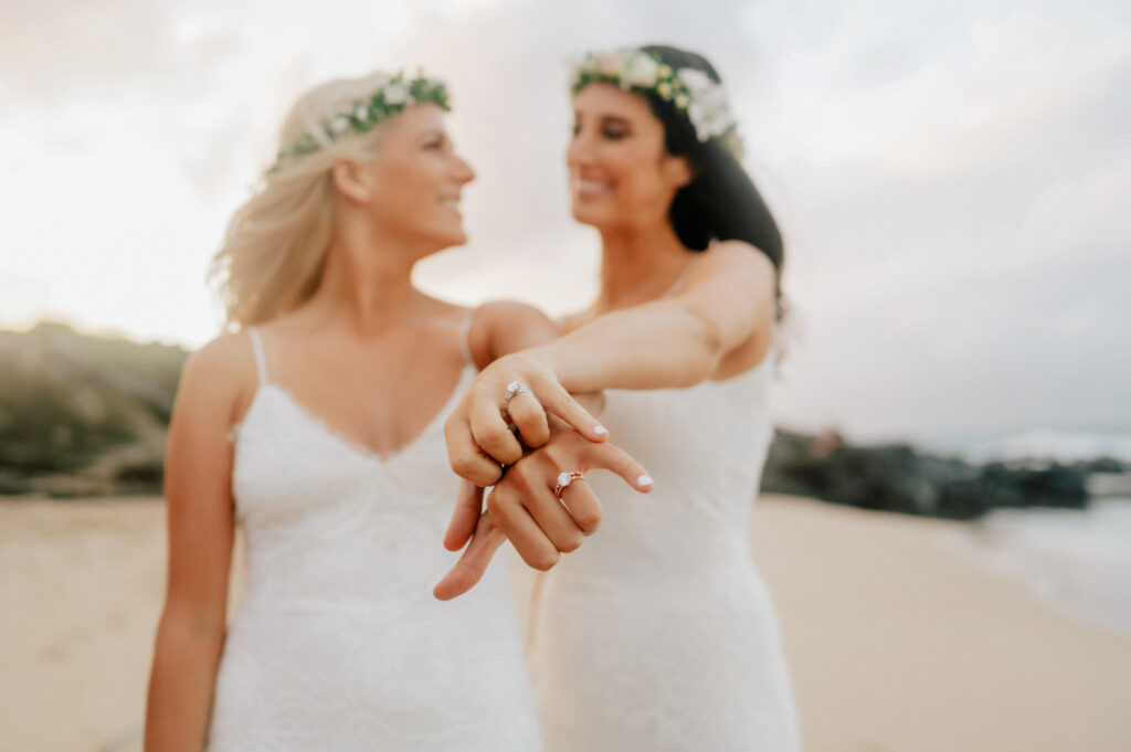 A joyful close-up of the brides showing off their wedding rings, symbolizing forever.