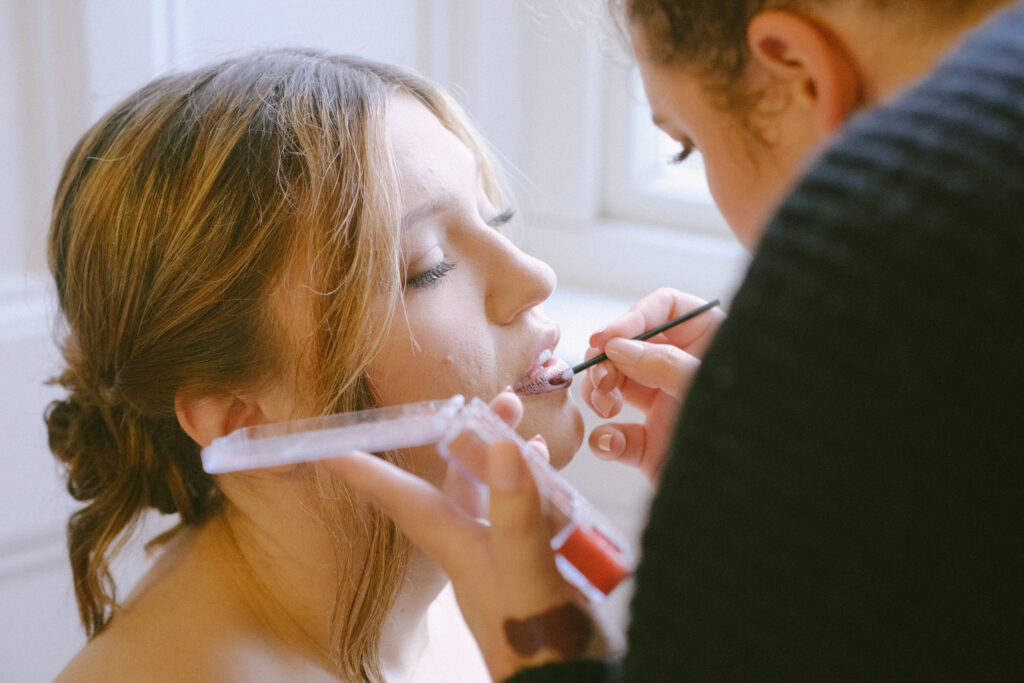 Makeup artist applies lipstick to bride, showcasing the final touches of her stunning look.
