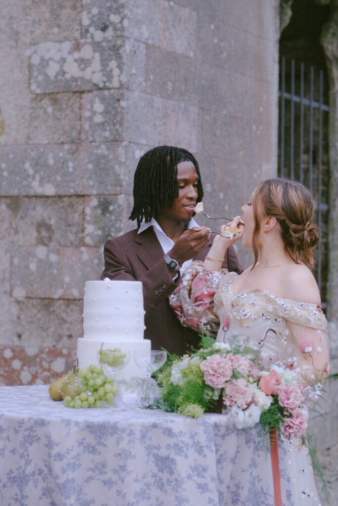 Groom lovingly feeds the bride cake, a candid and joyful moment full of laughter.